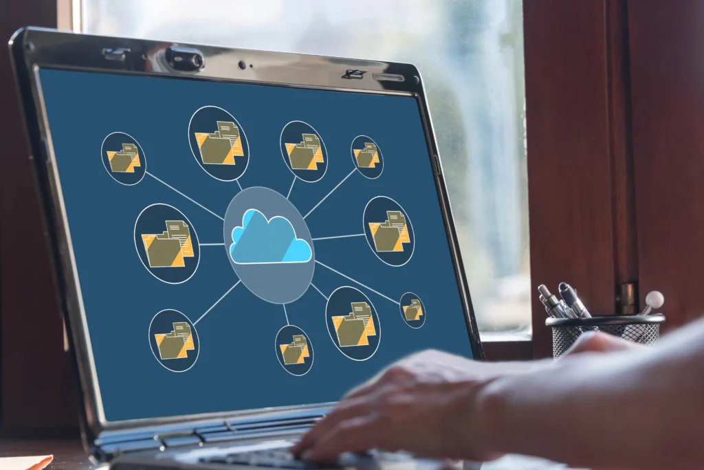 ノートパソコン画面にクラウドと複数のフォルダが表示されたファイル共有のイメージ