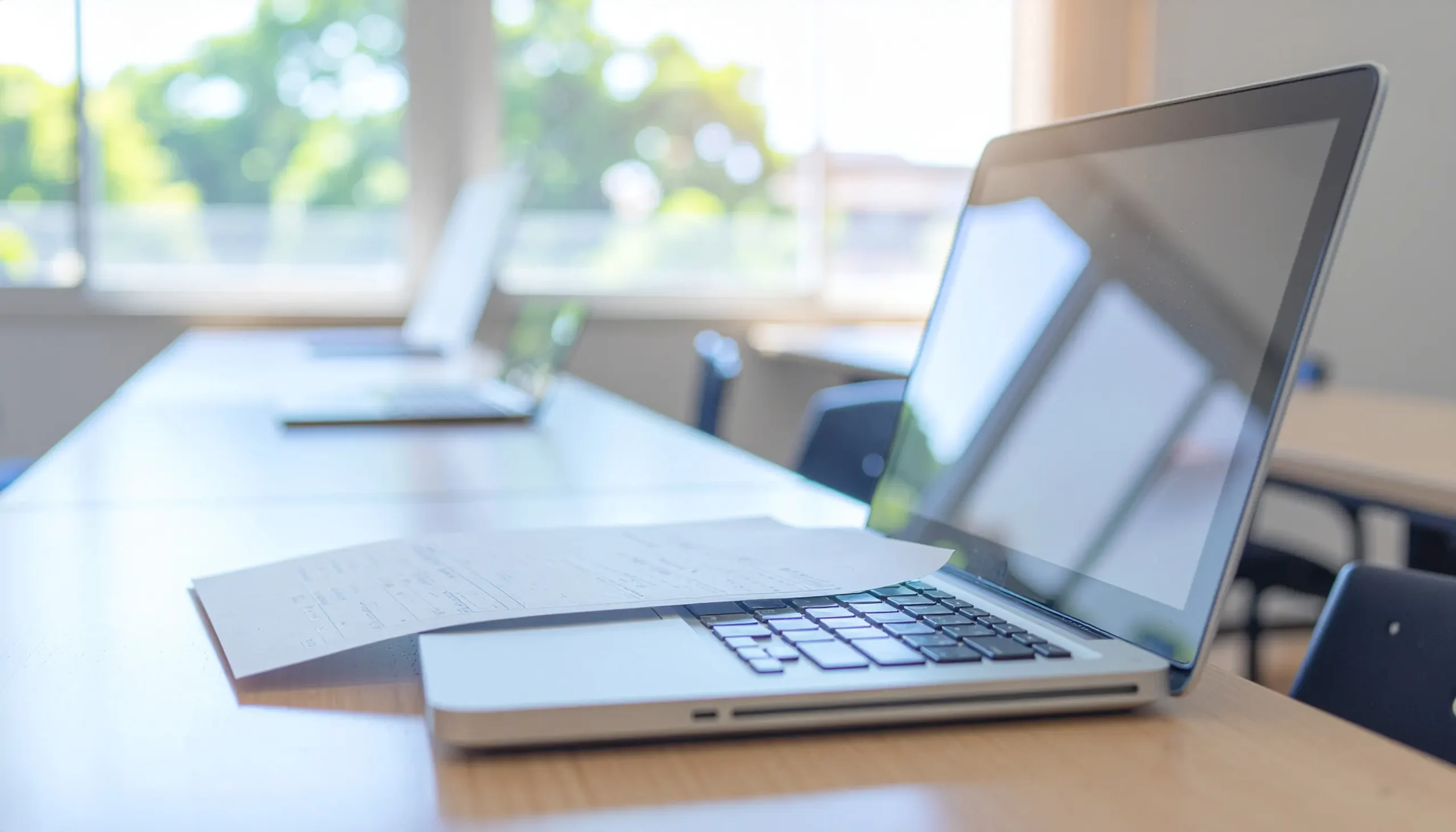 学校の教室の机に置かれたノートPCと資料